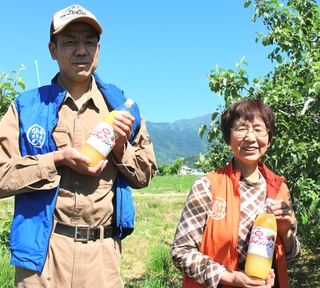 りんごジュースを手に持つ笠原果樹園さんの写真