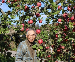 収穫期を迎えたりんごと笑顔の塚田農園さんの写真